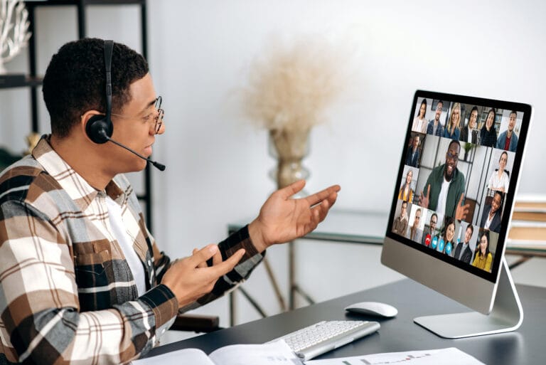 Online video conference, virtual meeting. Hispanic guy in a headset, manager, company employee, sits at the table, communicates with colleagues via video call, a group of partners discuss a project