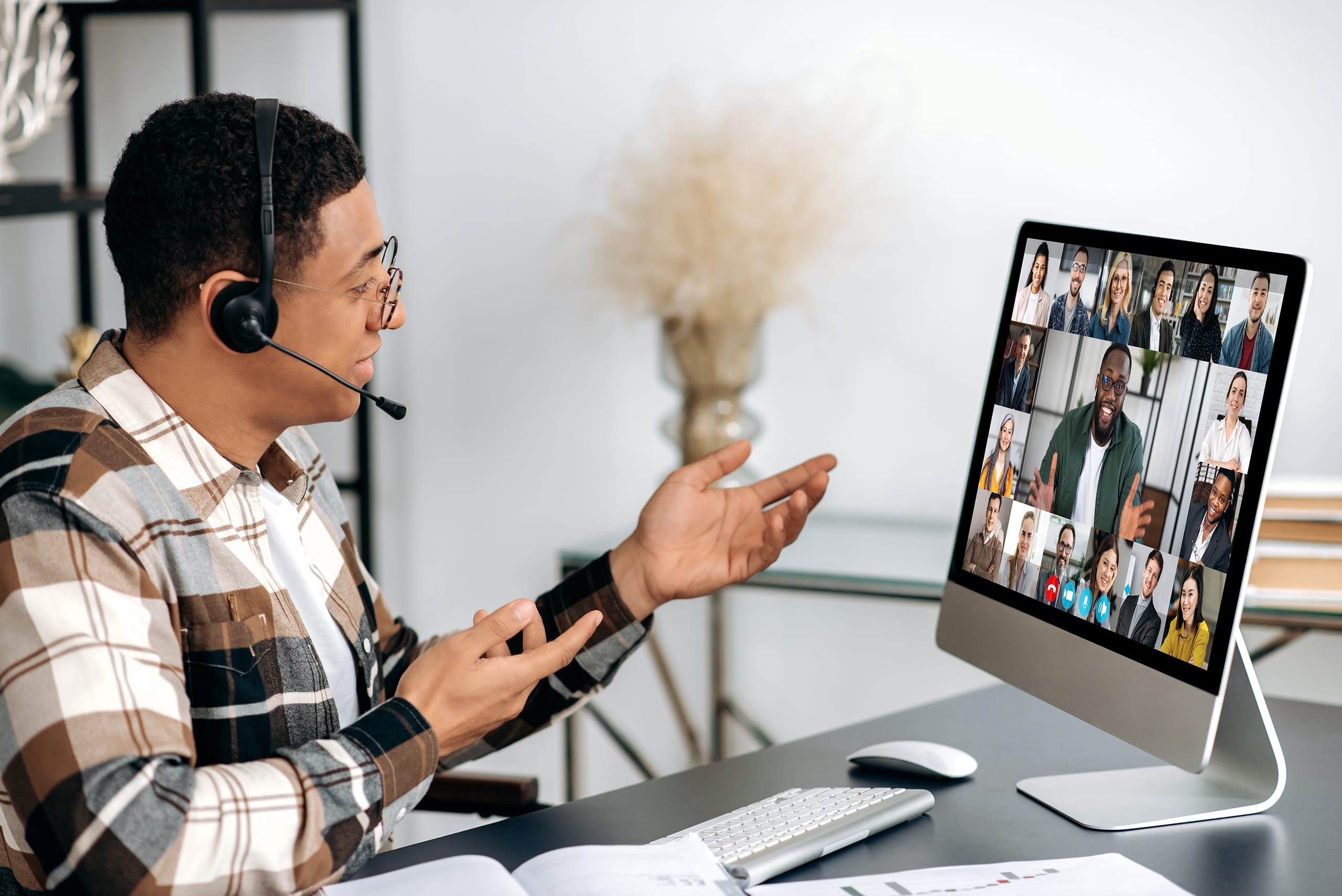 Online video conference, virtual meeting. Hispanic guy in a headset, manager, company employee, sits at the table, communicates with colleagues via video call, a group of partners discuss a project